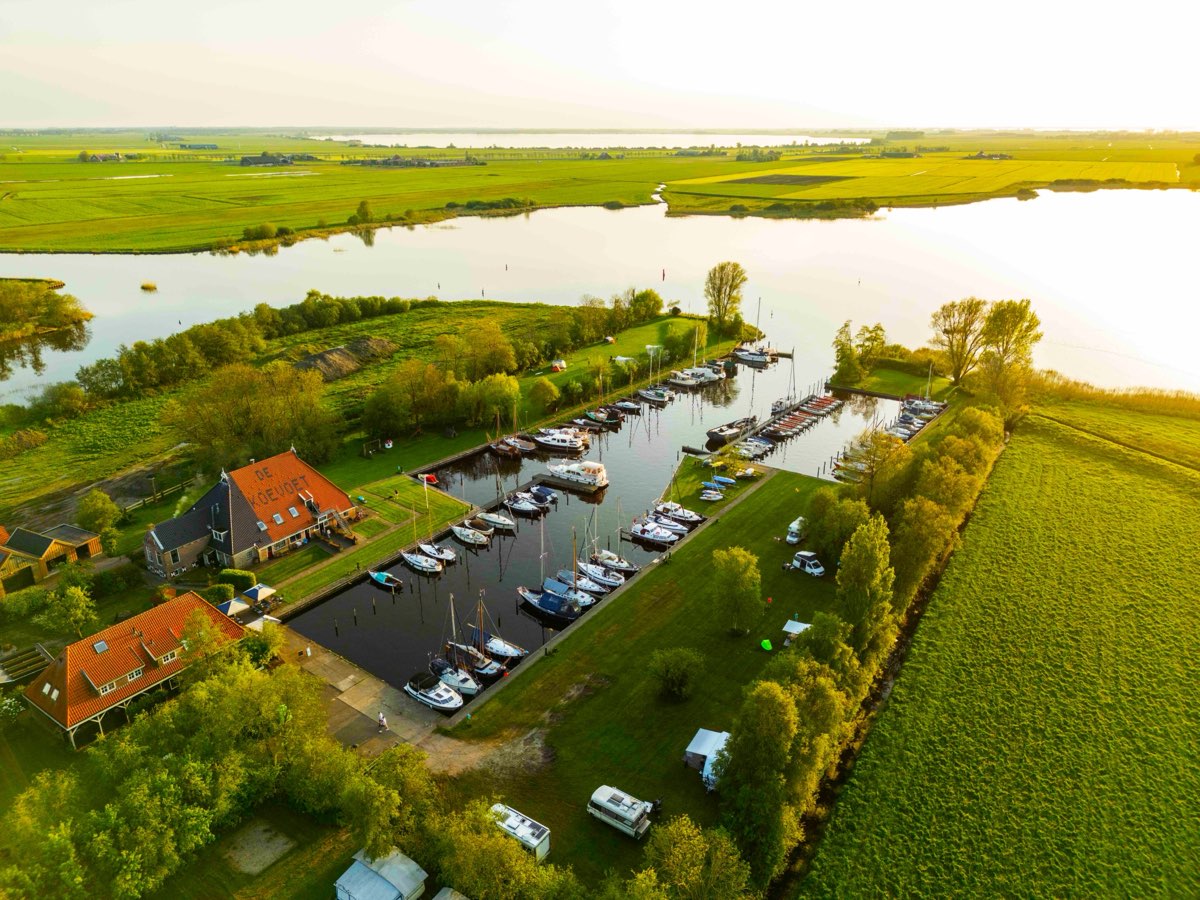 Luchtfoto van De Koevoet: de haven met boten, de boerderij met De Koevoet op het dak, en de Friese meren erachter